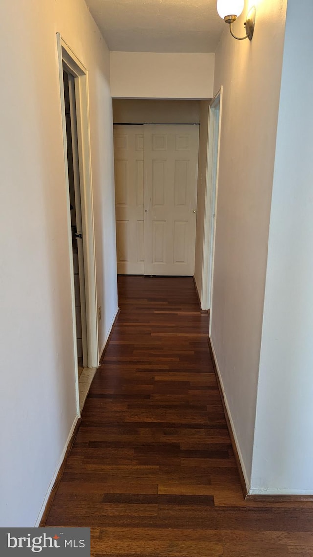 corridor with baseboards and wood finished floors