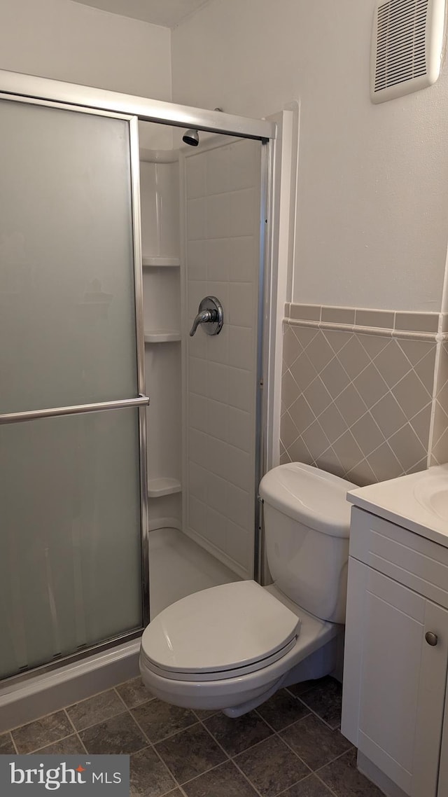 full bathroom featuring a shower stall, visible vents, tile walls, and toilet