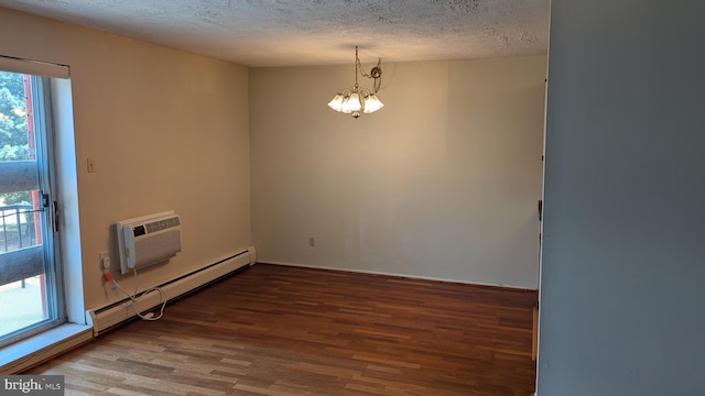 spare room featuring a chandelier, baseboard heating, plenty of natural light, and wood finished floors