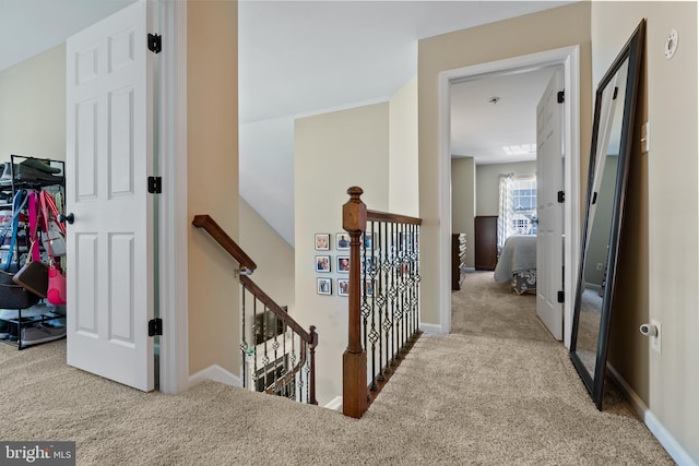 hall featuring carpet floors, baseboards, and an upstairs landing