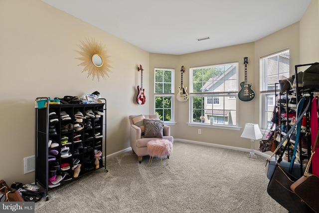 living area featuring carpet floors, a wealth of natural light, visible vents, and baseboards