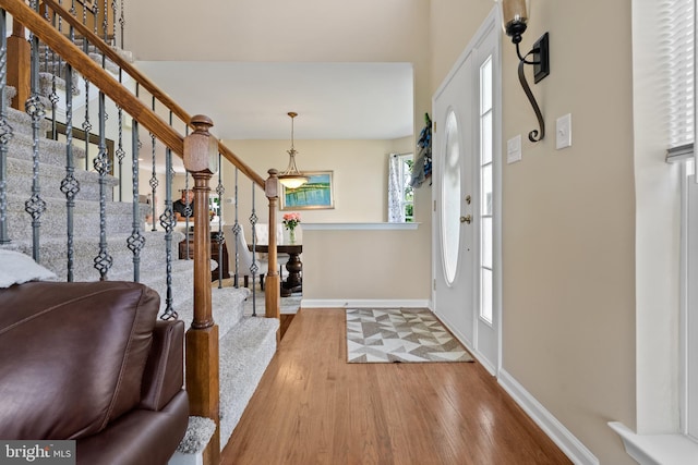 entryway featuring baseboards, stairway, and hardwood / wood-style floors