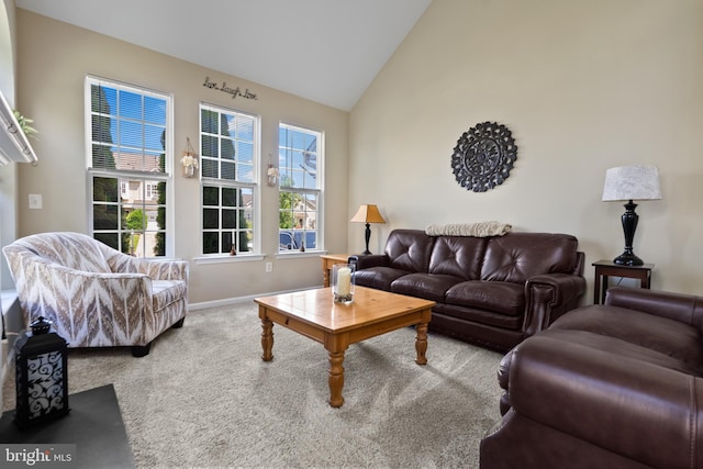 carpeted living area with lofted ceiling and baseboards