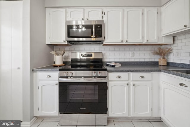 kitchen featuring tasteful backsplash, dark countertops, white cabinetry, appliances with stainless steel finishes, and light tile patterned flooring