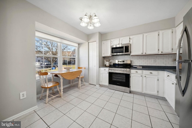 kitchen with dark countertops, white cabinets, tasteful backsplash, and stainless steel appliances