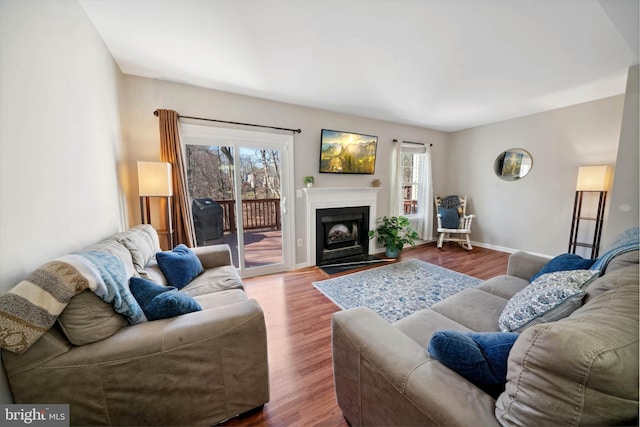 living room featuring a fireplace with flush hearth, wood finished floors, and baseboards