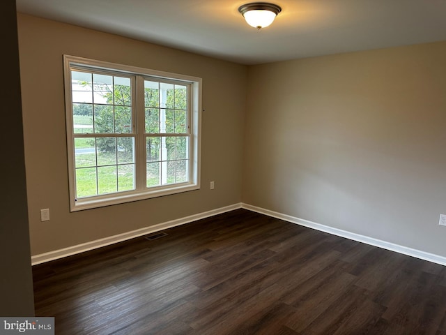 unfurnished room featuring baseboards, visible vents, and dark wood-type flooring