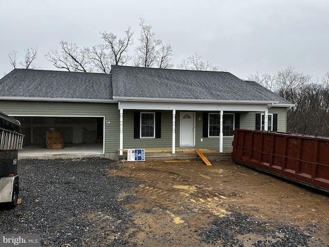 view of front of property with a garage, driveway, a porch, and roof with shingles