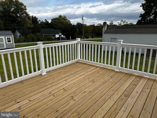 wooden deck with a yard, an outdoor structure, and a shed