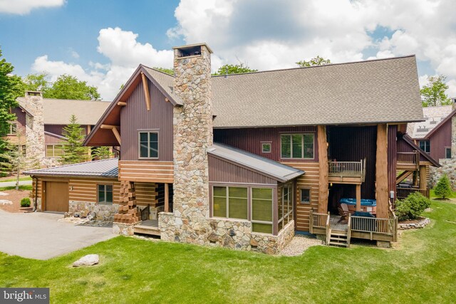 back of house featuring a chimney, metal roof, a yard, a patio area, and an attached garage