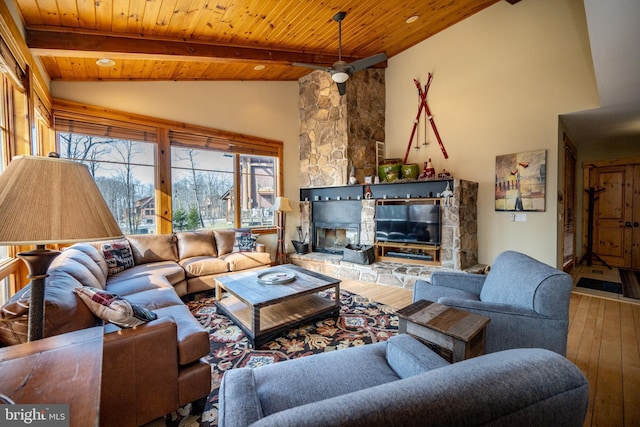 living area with high vaulted ceiling, beam ceiling, a stone fireplace, hardwood / wood-style flooring, and wood ceiling