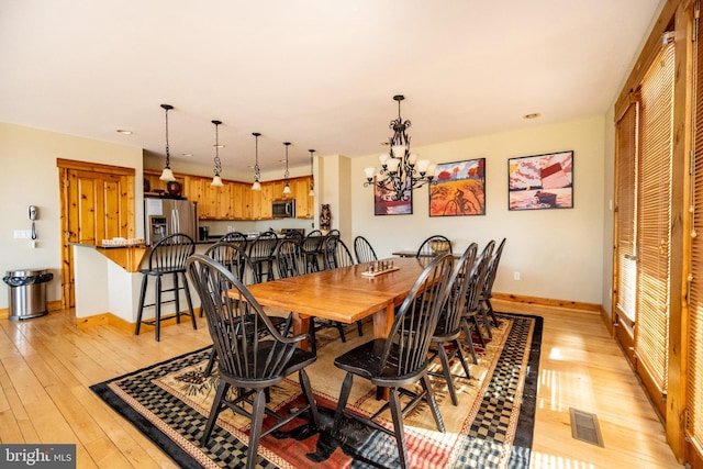 dining area with visible vents, baseboards, light wood-style floors, and an inviting chandelier