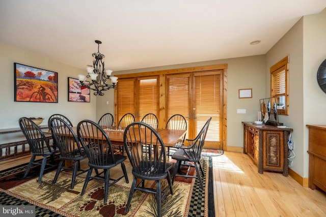 dining space featuring baseboards, light wood finished floors, and a chandelier