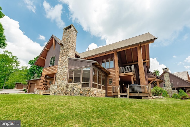 rear view of property featuring a balcony, a yard, a garage, and a chimney