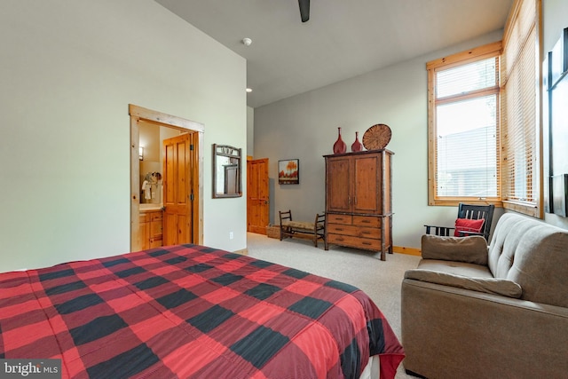 bedroom with high vaulted ceiling, ensuite bathroom, baseboards, light colored carpet, and ceiling fan