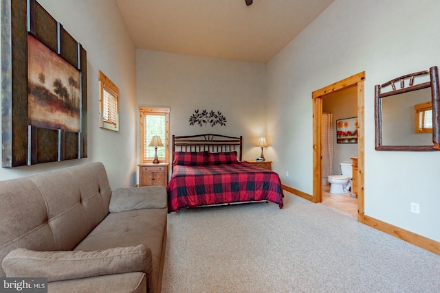 bedroom featuring light colored carpet, baseboards, and connected bathroom