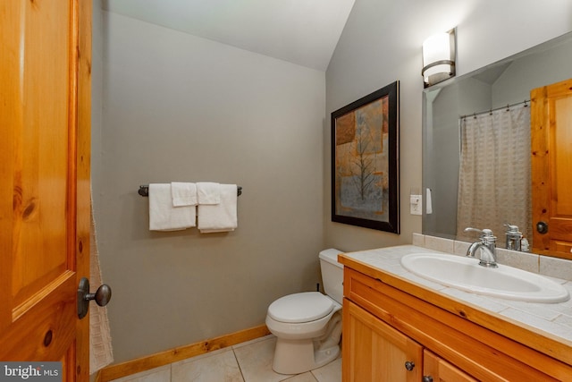 bathroom featuring tile patterned floors, toilet, baseboards, vanity, and vaulted ceiling