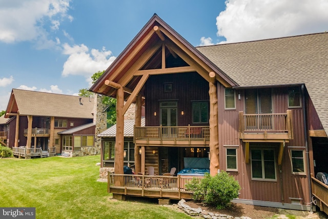 back of property with a lawn, a balcony, and a shingled roof