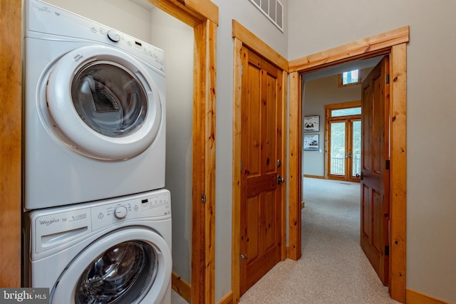 clothes washing area featuring stacked washer / drying machine, visible vents, carpet flooring, and laundry area