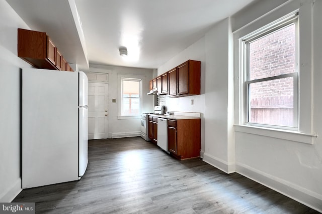 kitchen featuring brown cabinets, white appliances, baseboards, and dark wood-style flooring