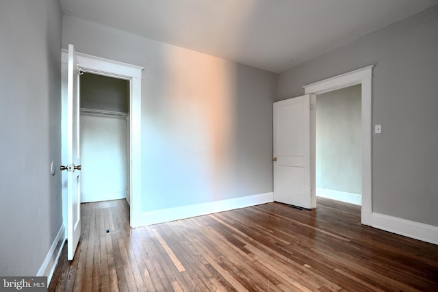 unfurnished bedroom featuring a closet, wood-type flooring, and baseboards