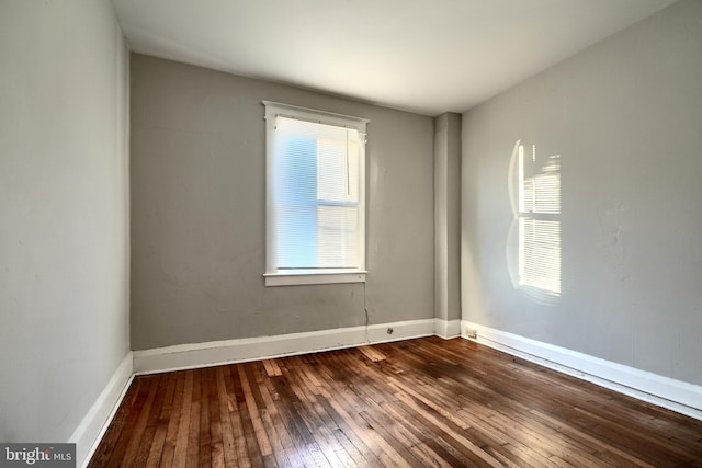 spare room featuring hardwood / wood-style flooring and baseboards