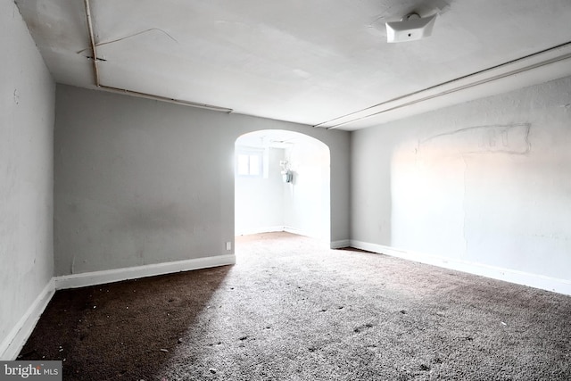 unfurnished room featuring arched walkways and baseboards