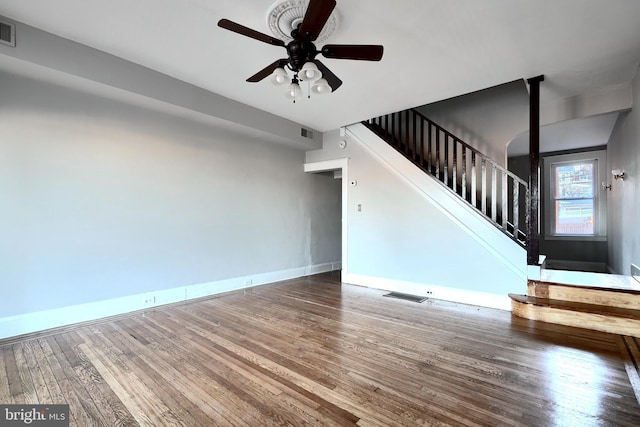 unfurnished living room with visible vents, stairs, baseboards, and wood finished floors