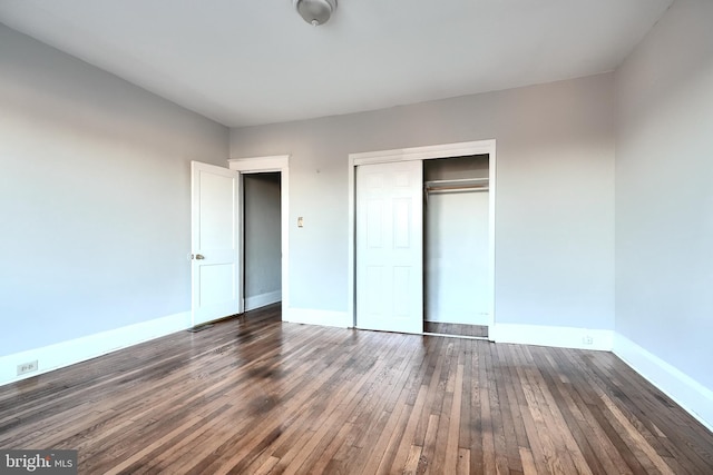 unfurnished bedroom with a closet, baseboards, and hardwood / wood-style floors