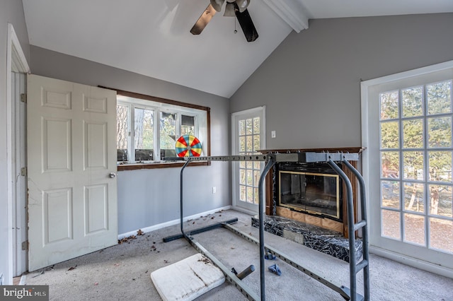 workout room with a glass covered fireplace, a healthy amount of sunlight, vaulted ceiling, and carpet flooring