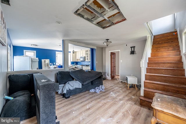 living room featuring light wood-type flooring, stairway, and baseboards