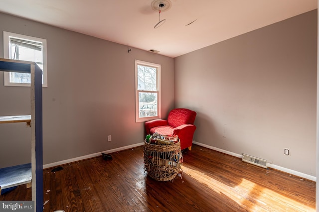 living area featuring baseboards, visible vents, and hardwood / wood-style floors