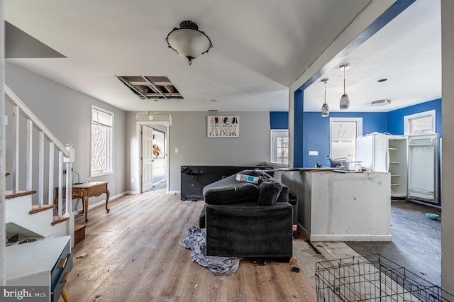 living area with baseboards, stairway, and wood finished floors