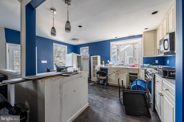 kitchen featuring dark wood-style floors, plenty of natural light, stainless steel range, and pendant lighting