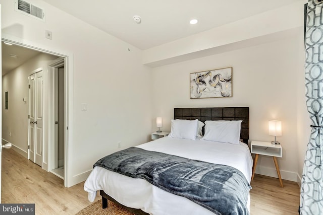 bedroom with light wood-type flooring, visible vents, and baseboards