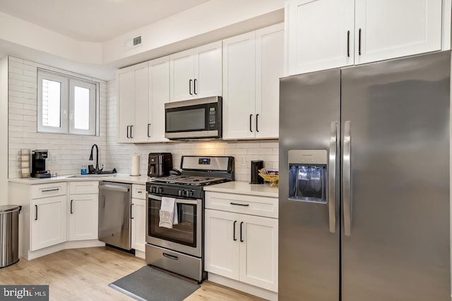 kitchen featuring light countertops, visible vents, appliances with stainless steel finishes, white cabinets, and a sink