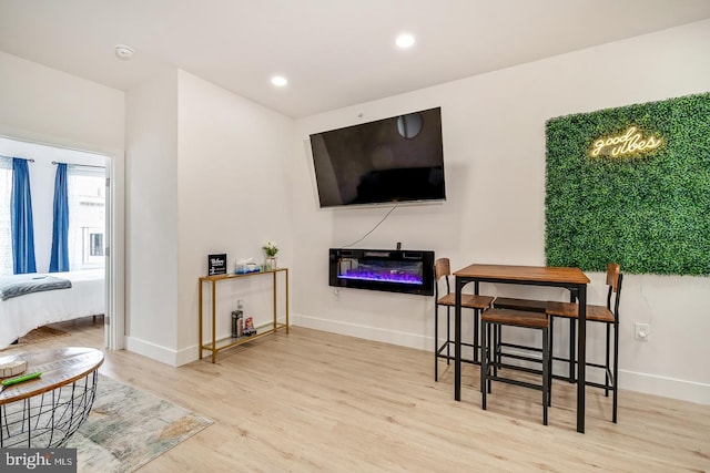 interior space featuring baseboards, a glass covered fireplace, wood finished floors, and recessed lighting