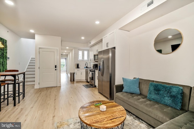 living area with light wood finished floors, visible vents, stairway, and recessed lighting