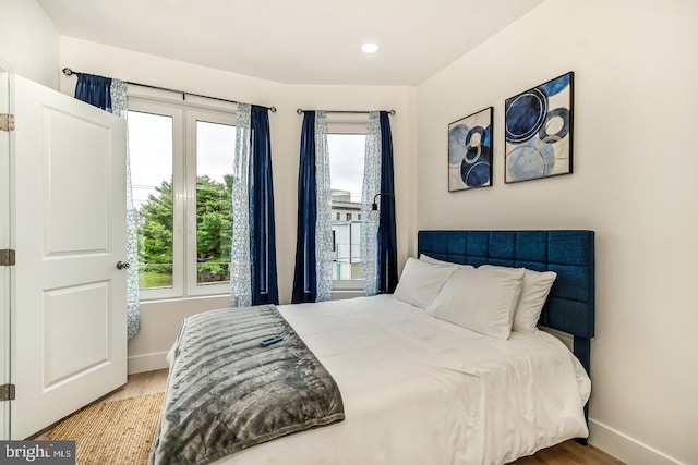 bedroom with light wood-style flooring, multiple windows, and baseboards