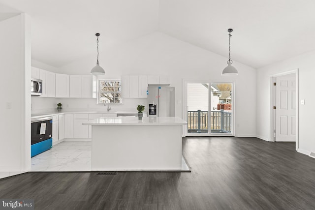 kitchen featuring decorative light fixtures, stainless steel appliances, light countertops, white cabinetry, and a sink