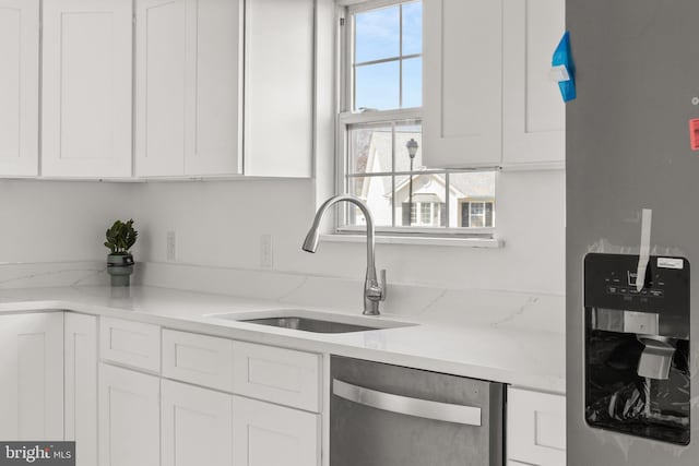 kitchen with appliances with stainless steel finishes, white cabinets, and a sink