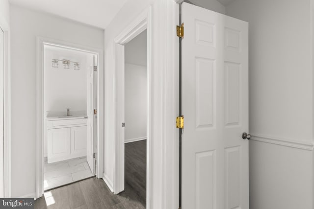 corridor with dark wood-style flooring and a sink