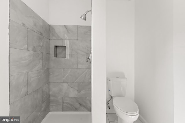 bathroom with toilet, a stall shower, and baseboards