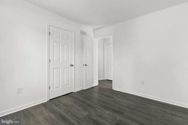 unfurnished bedroom with baseboards, visible vents, and dark wood finished floors