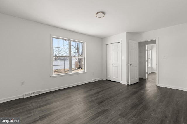 unfurnished bedroom featuring baseboards, visible vents, and dark wood-style flooring