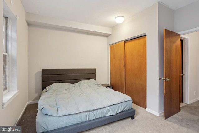 bedroom with a closet, light carpet, and baseboards