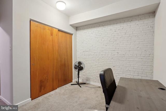 carpeted home office featuring baseboards and brick wall