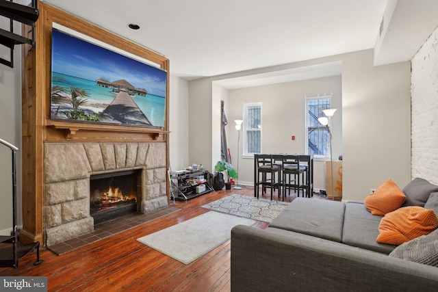 living room featuring a stone fireplace and hardwood / wood-style flooring