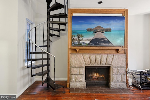 interior details with a stone fireplace, wood finished floors, and baseboards