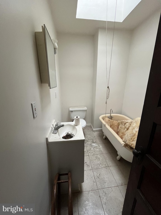 bathroom featuring a sink, toilet, a skylight, and a washtub